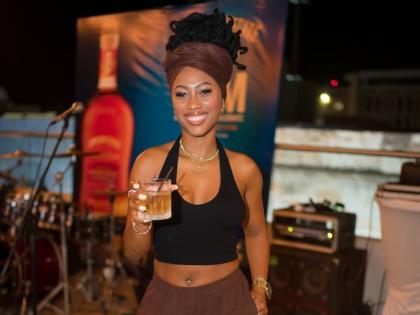 Trishana Williams, financial service representative, holds her Appleton Estate Spanish Sherry cocktail in hand, dressed in casual chocolate brown slacks, a matching head scarf, and a black halter.
