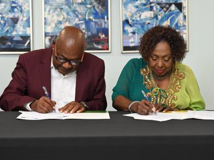 Minister of Culture, Gender, Entertainment and Sport, Olivia Grange (right), and Jamaica Football Federation President Michael Ricketts sign documents committing Jamaica to being one of four hosts of the 2031 FIFA Women’s World Cup at the ministry’s Tr