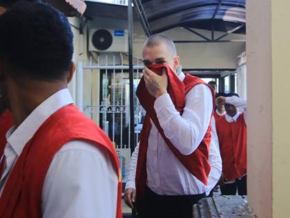 wiss tourist Luzian Andrin Zgraggen, who is accused of insulting the Balinese Hinduism’s sacred Day of Silcence in social media posts, covers his face upon arrival at the district court in Denpasar, Bali, Indonesia, Thursday.