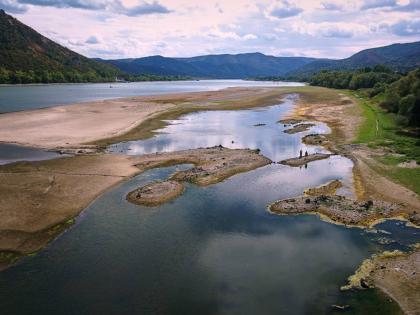People walk on sandbanks exposed by record-low water levels in the Danube River after drought and extreme heat near Nagymaros in Hungary, on August 18, 2026.