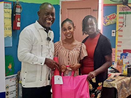 Amoy Beckford (centre) receives back-to-school supplies from Portmore Mayor Leon Thomas for her children, who will be transitioning to Gregory Park Primary School, as principal Jennifer James Ferguson shares in the moment.