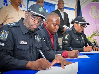 President of the St John Heights Neighbourhood Watch, Yian Shettlewood (centre), signs the memorandum of understanding with Assistant Commissioner of Police in charge of the Community Safety and Security Branch, Charmaine Shand (right); and Senior Superint