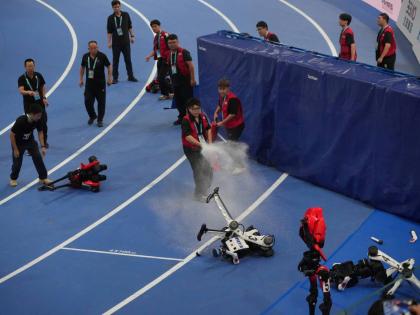 Officials extinguish the fire to a Humanoid robot after hitting the barrier at the end of the 100m race during the World Humanoid Robot Games in Beijing, China, on Tuesday. - AP photo