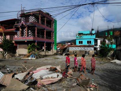 People walk past damage in the aftermath of flash floods in Devighat in the Nuwakot district in Nepal on Thursday. - AP photo
