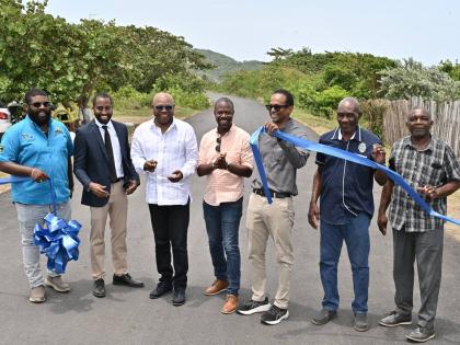 Minister of Tourism, Edmund Bartlett (third left) cuts the ribbon to officially open the rehabilitated roadway between Robins Bay and Strawberry Fields, St Mary, on Wednesday. Sharing in the moment are (from left) Mark Knight, managing director, Wadmar Con