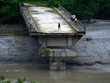 People stand on remnants of a bridge that spanned across the Trishuli River and was washed away in flash floods in Dhading District, Nepal, on Sunday.