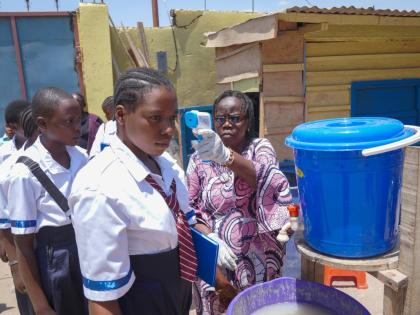 A school official checks students' temperatures as they enter school, on the first day of the new school year amid the Ebola virus outbreak, in Ituri, Congo, Tuesday, Sept.1, 2026. (AP Photo/Dieudonne Dirole)