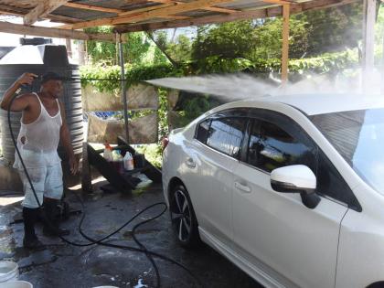 Michael Barnett washes a car with water from one of his tanks at his Kingston Gardens Public Car Wash in central Kingston on Tuesday.