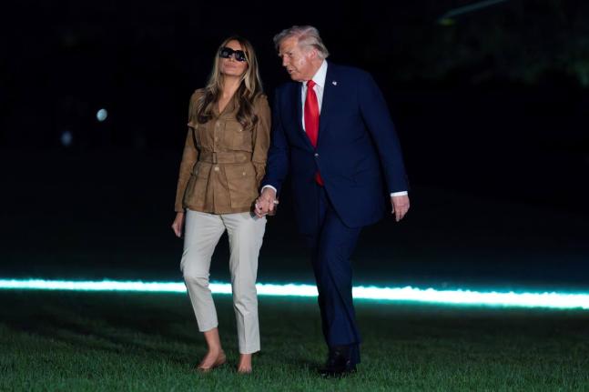 President Donald Trump holds hands with first lady Melania Trump as they walk on the South Lawn upon their arrival to the White House, in Washington on Thursday.