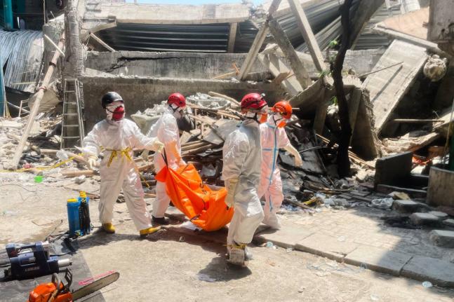 Rescuers carry the body of a victim of a collapsed building at an Islamic boarding school in Sidoarjo, East Java, Indonesia yesterday.