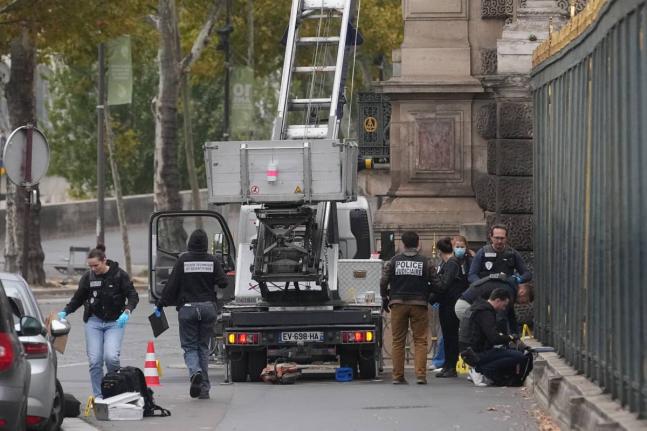 Police officers look for clues by a basket lift used by thieves at the Louvre museum in Paris. 