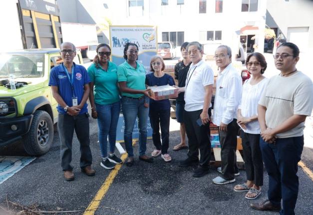 Abigail Whittaker-Clarke (second left) and Elecia Whittingham-Gayle (third left) collect a donation from the Burmese community, on behalf of the Western Regional Health Authority staff members. 
