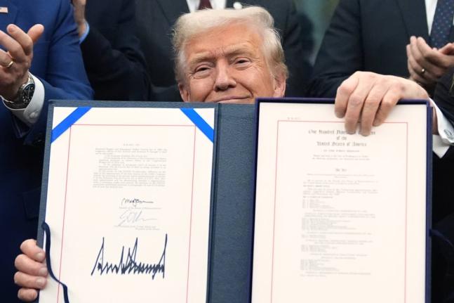 President Donald Trump displays the signed the funding bill to reopen the government, in the Oval Office of the White House, Wednesday, November 12, 2025, in Washington. (AP Photo/Jacquelyn Martin)