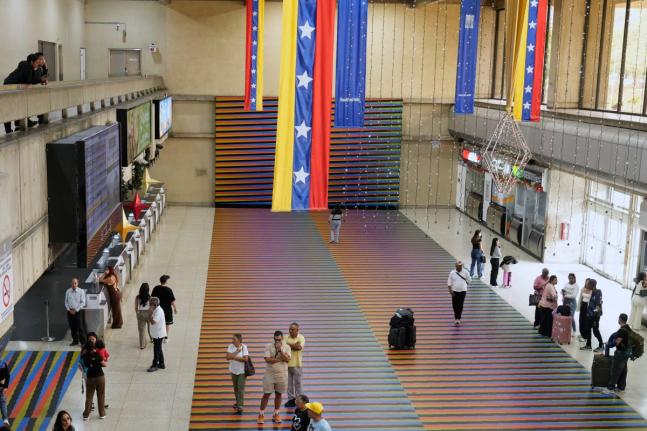Travellers wait in the main hall of the Simon Bolivar Maiquetia International Airport in Maiquetia, Venezuela, Sunday, November 23, 2025, after several international airlines cancelled flights following a warning from the US Federal Aviation Administration