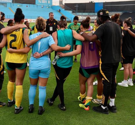 Reggae Girlz coach Hubert Busby takes his charges through a team talk.