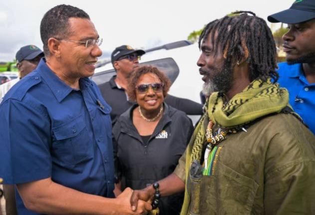 Prime Minister Dr Andrew Holness, shaking hands with Chief of the Accompong Maroons in St Elizabeth, Richard Currie, during a visit to the community on Sunday, November 30. Looking on is Minister of Culture, Gender, Entertainment and Sport, Olivia Grange.