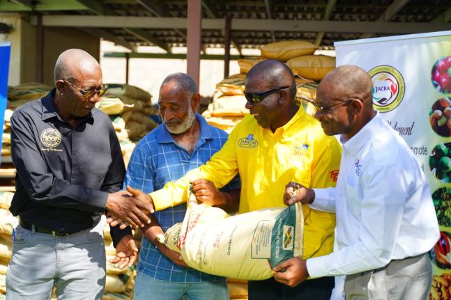 President of the Jamaica Coffee Growers Association, Donald Salmon (left), shares a handshake with Dr Norman Grant (second right), president of the Jamaica Coffee Exporters Association, while Wayne Hunter (right), acting director general for the Jamaica Ag