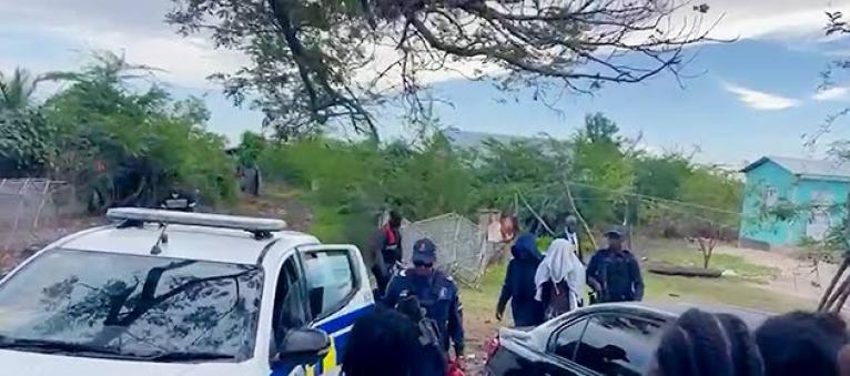 Police personnel escort the suspect in yesterday’s triple murder in Clarendon to a service vehicle. 