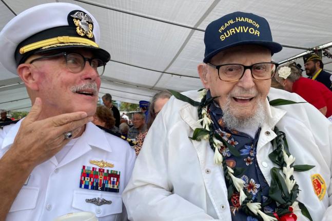 Ira Schab (right) who survived the attack on Pearl Harbor as a sailor on the USS Dobbin, talks with reporters while sitting next to his son, retired Navy Commander Karl Schab, in December 2022, in Pearl Harbor, Hawaii. 