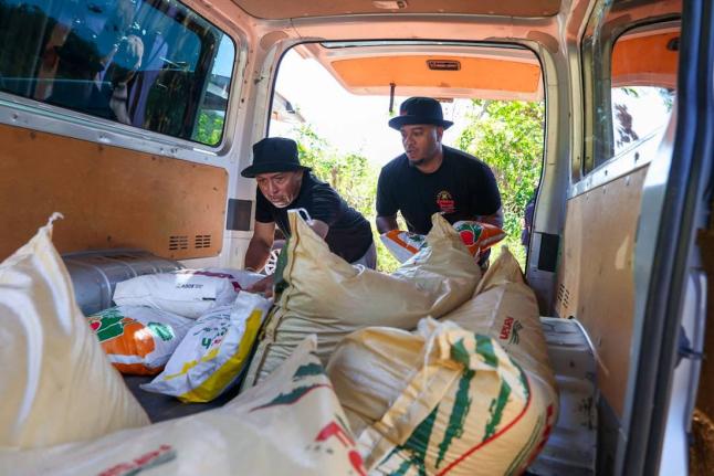 Golden Krust Vice President of Marketing, Steven Clarke (right), and Director of Quality Control, Regulatory Affairs & Research and Development, Christopher Hylton, prepare fertilizers for farmers in St Elizabeth. The initiative forms part of relief effort