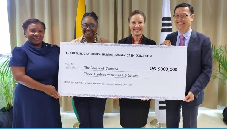 Minister of Foreign Affairs and Foreign Trade, Senator Kamina Johnson Smith (second right), receives a cheque valued at US$300,000 from Chargé d’Affaires at the Embassy of the Republic of Korea, Jin-wook Kim (right), to support Jamaica’s recovery and 