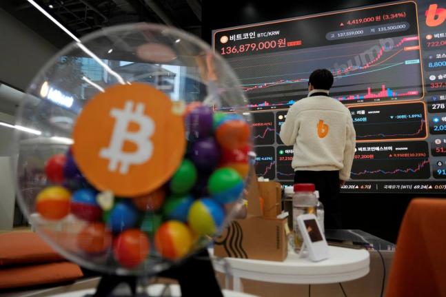 An employee watches an electronic signboard displaying the prices of bitcoin and other cryptocurrencies.  