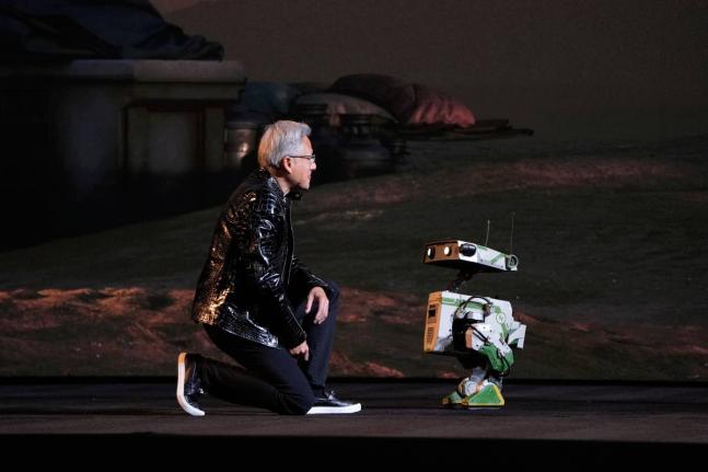 Nvidia founder and CEO Jensen Huang kneels in front of a robot during a Nvidia news conference ahead of the CES tech show Monday, January 5, 2026, in Las Vegas, USA.  