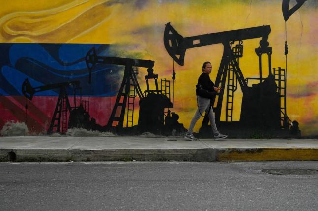 A local walks past a mural featuring oil pumps and wells in Caracas, Venezuela on January  6, 2026. 