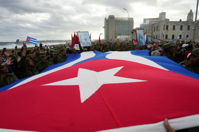People carry a Cuban flag during a government-organized rally protesting the killing of Cuban officers in Venezuela while United States forces captured Venezuelan President Nicolas Maduro and his wife, in Havana, Cuba on January 16, 2026.