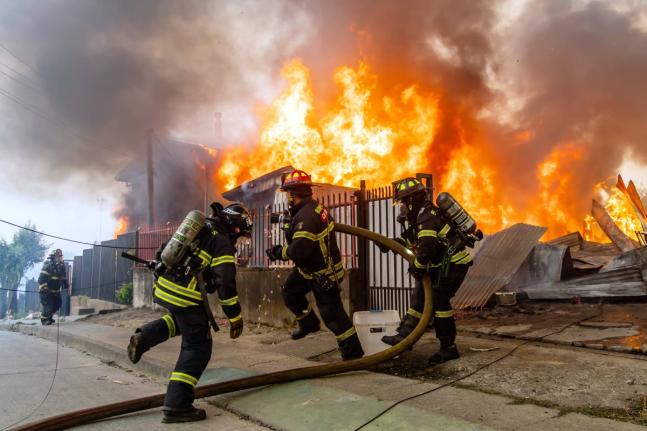 Firefighters battle a blaze at a house as wildfires burn in Lirquen, Chile.