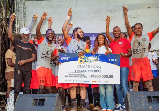 Members of Friends for Real, an Olympic Gardens-based football team celebrate winning the Pocket Rocket Foundation’s Six-A-Side Peace Through Sports Football Competition in 2024. Sharing in the moment is founder and Chairman of the foundation, Shelly-Ann