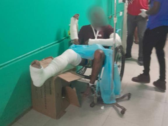 Seon Clarke, is seen in a wheelchair at Cornwall Regional Hospital with injuries to his hands and right leg, following an alleged assault while in police custody in St James.