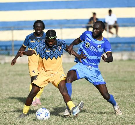 Racing United’s Nickyle Ellis (centre) shields the ball from Nickache Murray of Molynes United during their Jamaica Premier League encounter at the Constant Spring playfield yesterday.
