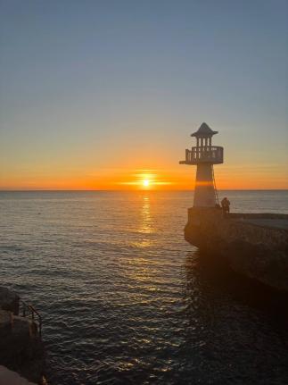 A sunset view with the Negril Lighthouse in the foreground, photographed from the Negril Huts property in West End.
