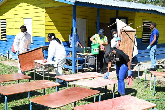 A joint team from the St James Police Division’s Community Safety and Security Branch (CSSB) and the Spot Valley High School Police Youth Club clears and cleans school furniture during ‘Operation Clean-Up’ at the infant department of Lethe Primary an
