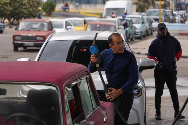 A driver refuels others wait in a long line behind to fill up at a gas station in Havana, Cuba, Tuesday, January 27, 2026. (AP Photo/Ramon Espinosa)