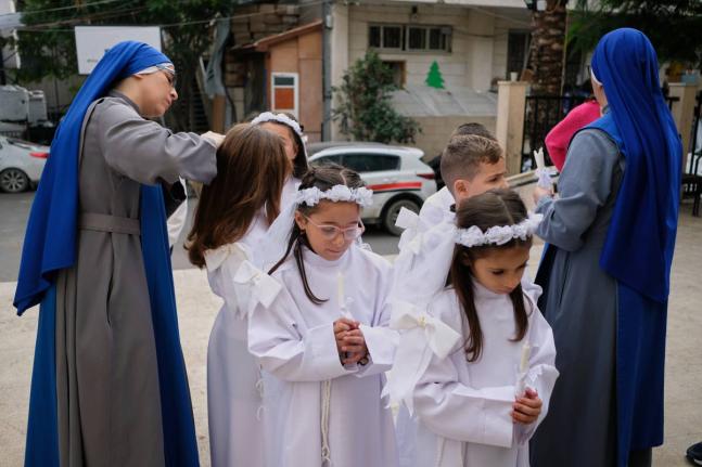 Children and nuns gather outside the Holy Family Catholic Church before attending a mass ahead of Christmas celebrations in Gaza City.