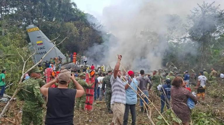 People stand around a military cargo plane that crashed after taking off from Puerto Leguizamo, Colombia, a remote municipality in the Amazonian province of Putumayo, Monday, March 23, 2026.
