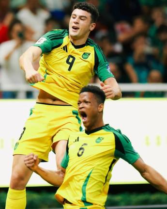 Reggae Boyz players Bailey Cadamarteri (left) and Richard King ceelebrate the former's 18th-minute goal during a FIFA playoff game against New Caledonia at the Guadalajara Stadium yesterday.