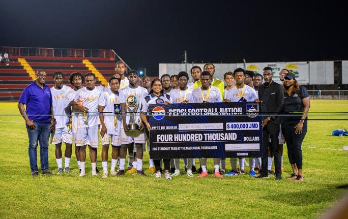 Pepsi Jamaica Brand Manager Ashli-Raye Recas (seventh from left) hands over a symbolic J$400,000 developmental cheque to members of the victorious JPL U-23 All-Star team, following the inaugural Made4Goal Championship Showcase at the Anthony Spaulding Spor