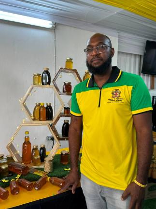 Senior Plant Protection Officer in the Ministry of Agriculture, Fisheries and Mining’s Apiculture Unit, Gregory Lynch, stands before a table stacked with honey, at the 72nd staging of the Denbigh, Agricultural, Industrial and Food Show at the Denbigh Sho