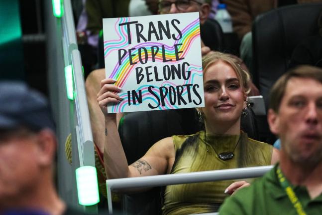 A person holds a “trans people belong in sports” sign during the first half of a WNBA basketball game between the Seattle Storm and the Indiana Fever, Tuesday, July 28, in Seattle. 
