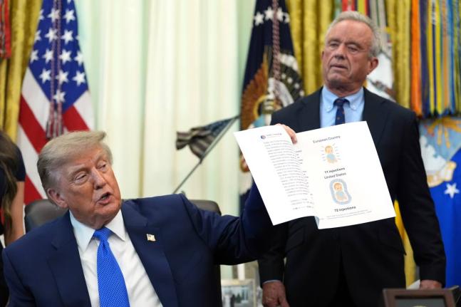 President Donald Trump holds up an image taken from his Truth Social account as Health and Human Services Secretary Robert F. Kennedy Jr. watches during a meeting to sign an executive order about vaccines, Monday, Aug. 10, 2026, in the Oval Office of the W