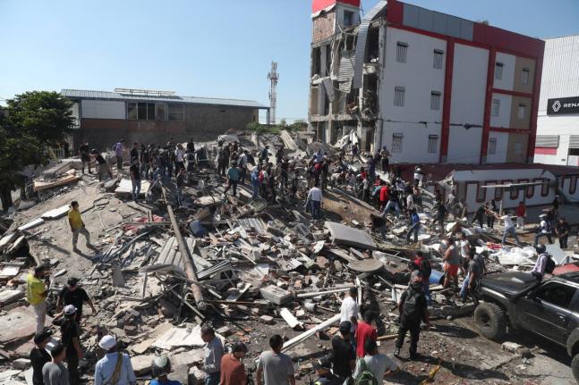 Residents and rescue workers search through the rubble of a collapsed building after an earthquake struck Cali, Colombia, Monday.