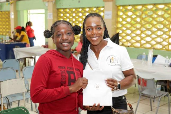 Olympian Veronica Campbell Brown (right) hands over a VCB Foundation gift to a student at last year’s Back-to-School Health and Wellness Fair at Vere Technical High School in Clarendon.
