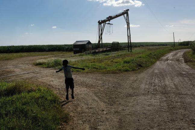 A youth plays near the machine where the sugar cane is weighed in the Lima batey, or neighborhood, in La Romana, where Central Romana Corporation, Ltd operates its sugar operations in Dominican Republic, November 17, 2021.