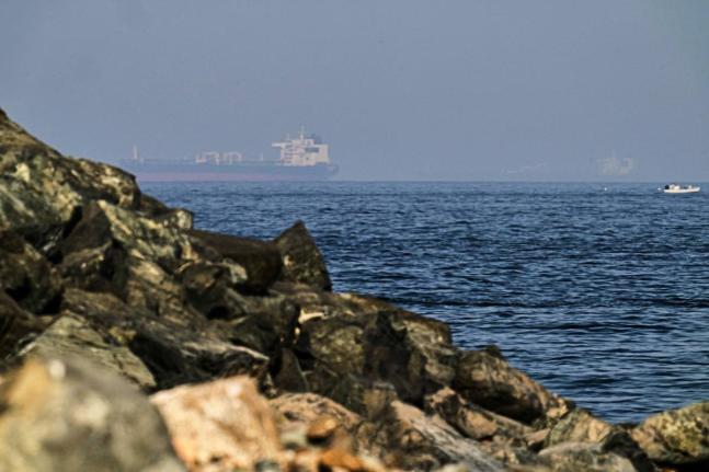 Cargo ships are seen at sea in the Gulf of Oman near the Strait of Hormuz, from a rocky shoreline near Khor Fakkan, United Arab Emirates, May 1, 2026.