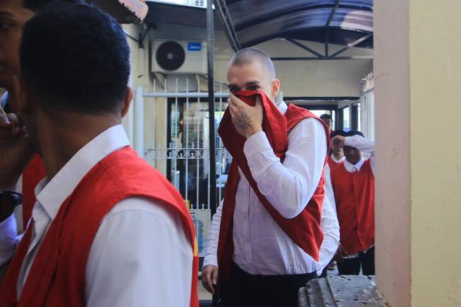 wiss tourist Luzian Andrin Zgraggen, who is accused of insulting the Balinese Hinduism’s sacred Day of Silcence in social media posts, covers his face upon arrival at the district court in Denpasar, Bali, Indonesia, Thursday.