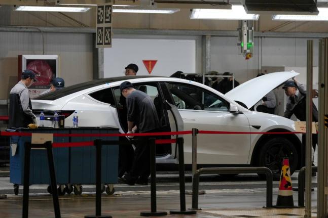 People work on the Tesla Model Y production line at the Tesla Gigafactory assembly plant during a media organized tour, in Shanghai, China, on Tuesday, April 14, 2026. - AP file photo