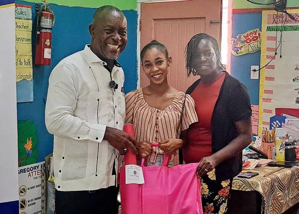 Amoy Beckford (centre) receives back-to-school supplies from Portmore Mayor Leon Thomas for her children, who will be transitioning to Gregory Park Primary School, as principal Jennifer James Ferguson shares in the moment.